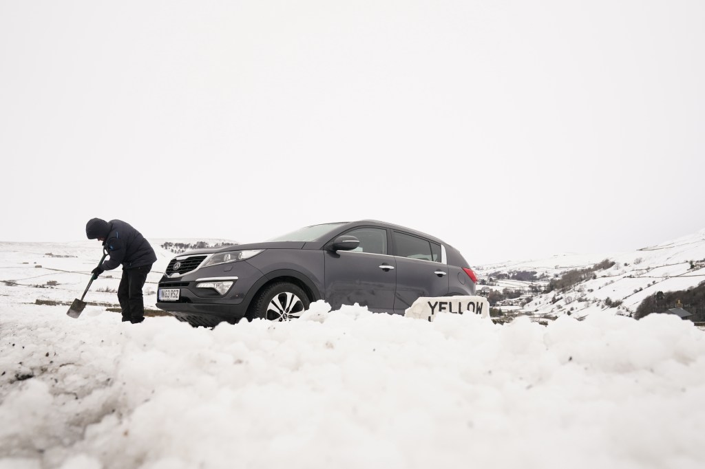 Man digging his car out from the snow. Winter driving is dangerous.