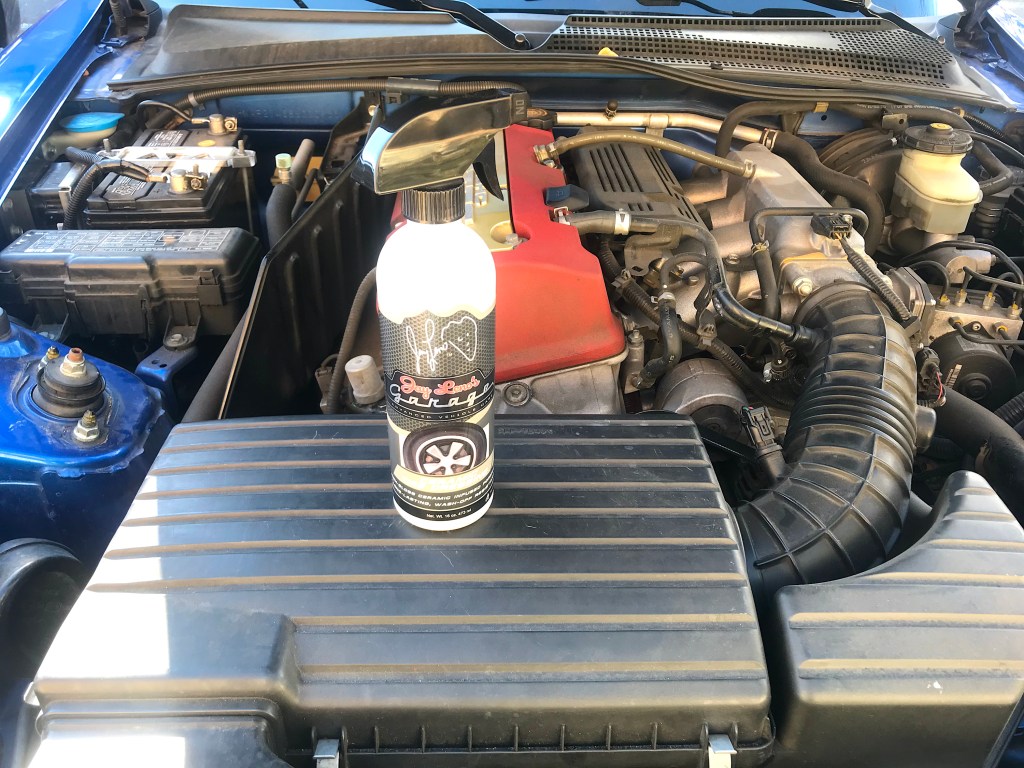 My S2000's dirty engine bay with a bottle of Jay Leno's tire shine.