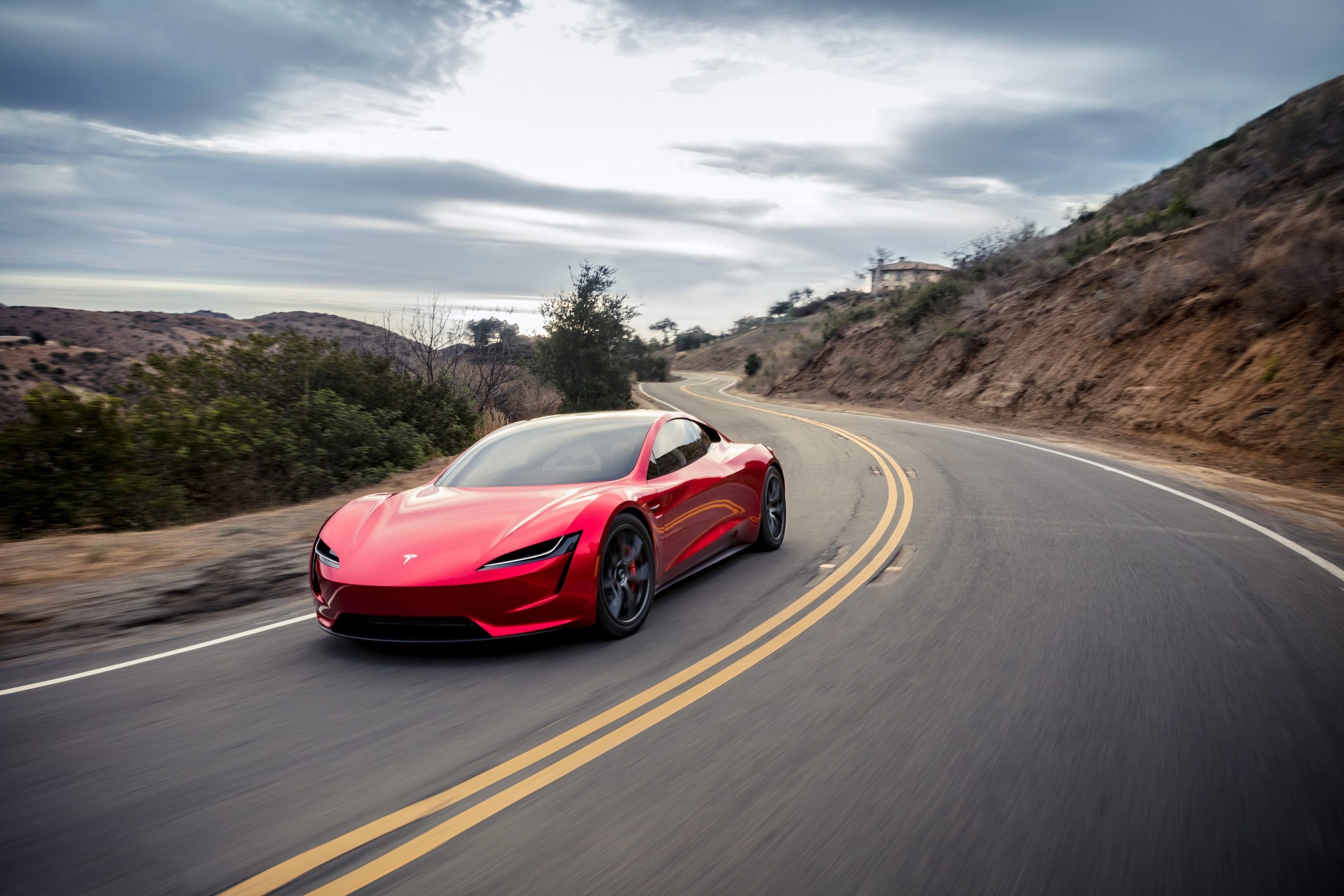 A red Tesla Roadster on a back road