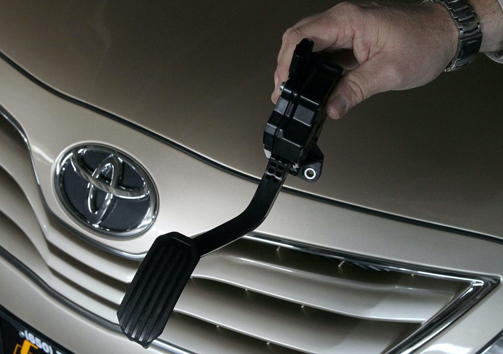 A mechanic holds a recalled accelerator pedal for a Toyota Camry.