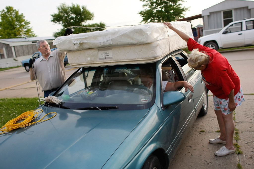 People tie a mattress to the top of a car as they evacuate from their home after waters from the flooding Mississippi River broke through a levee overnight.