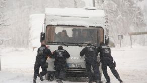 A camper RV motorhome stuck in winter snow and being pushed by police officers in the Harz Mountains