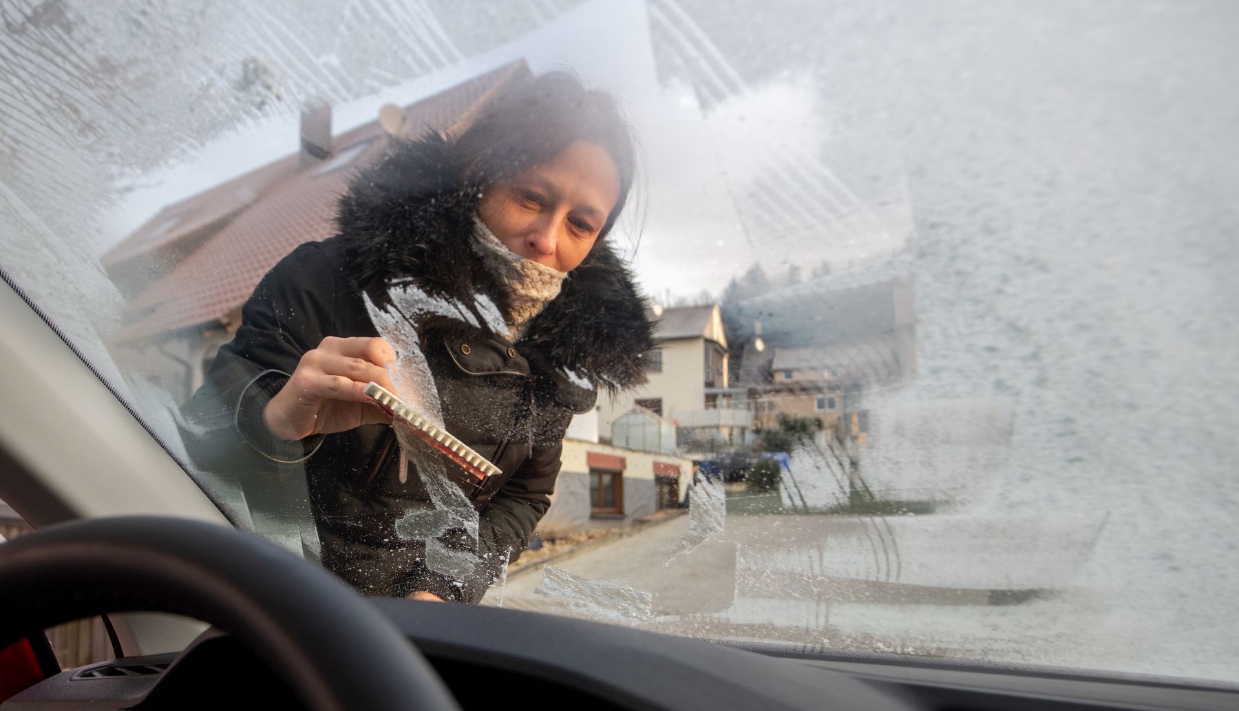 A woman scraping a frozen car windshield window in Baden-Wuerttemberg, Ballmertshofen, Dischingen, Germany