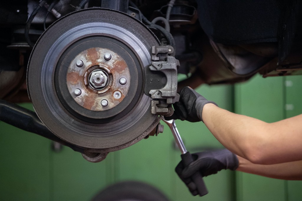 A car mechanic changes the brake disc of a Range Rover Evoque in a garage.