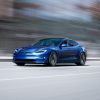 A 3/4 front view of a blue 2022 Tesla Model S driving on a street with a blurred background.