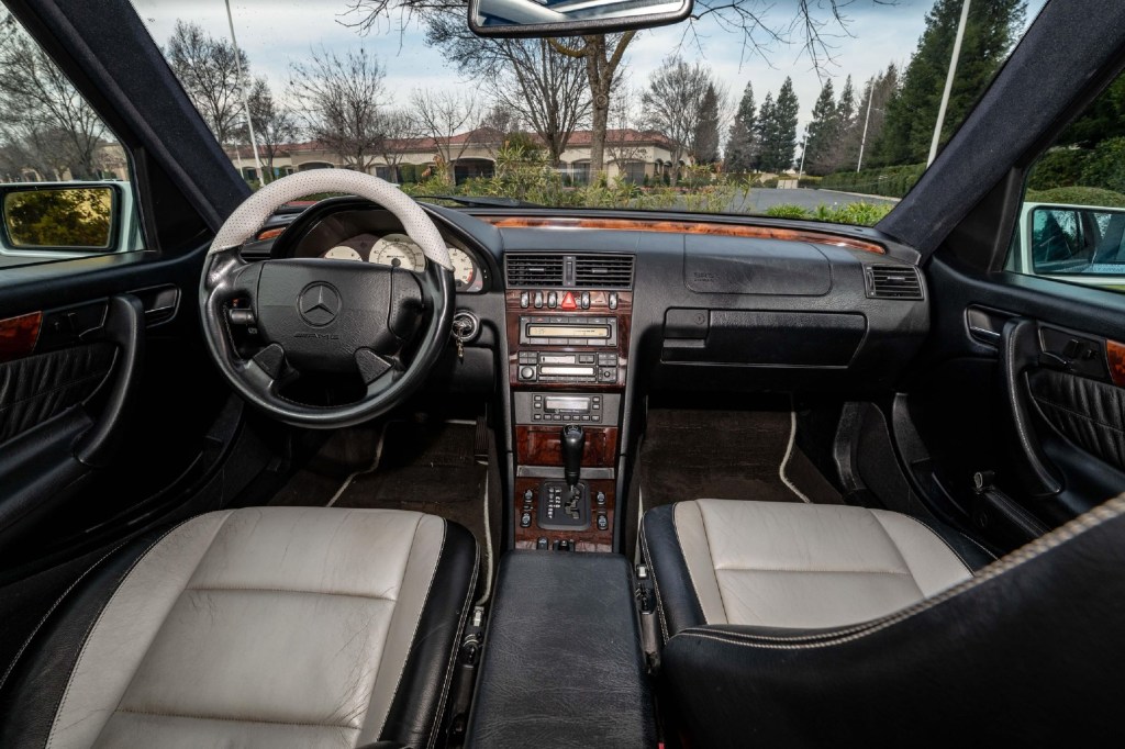 The white-and-black-leather front seats and wood-trimmed dashboard of a 1998 Mercedes C43 AMG