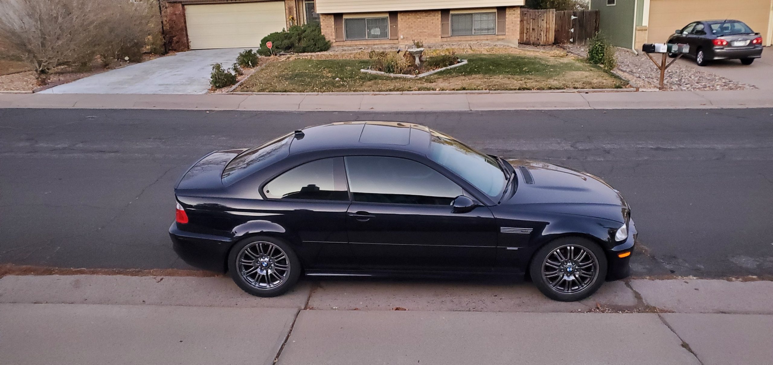A black 2004 BMW M3 shot in profile at dusk