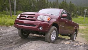 Red 2006 Toyota Tundra climbing a mountain trail in front of a ski lift and wooded hills.