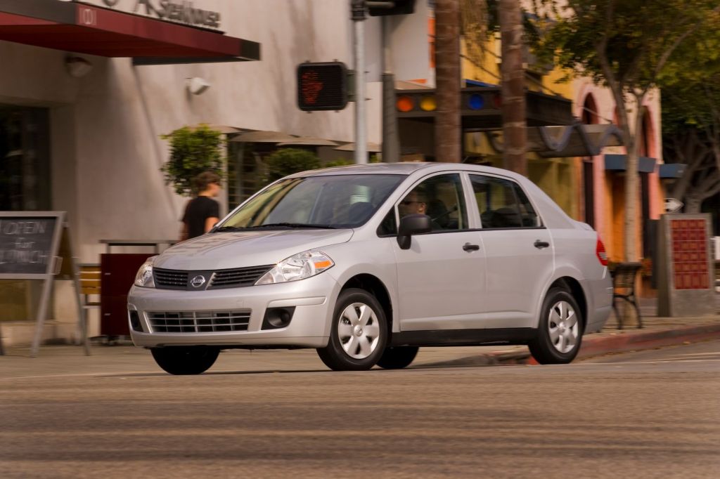 A 2009 Nissan Versa compact sedan model with a silver gray paint color option stopped while attempting to turn