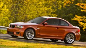 An orange 2011 BMW 1 Series M Coupe on a country road