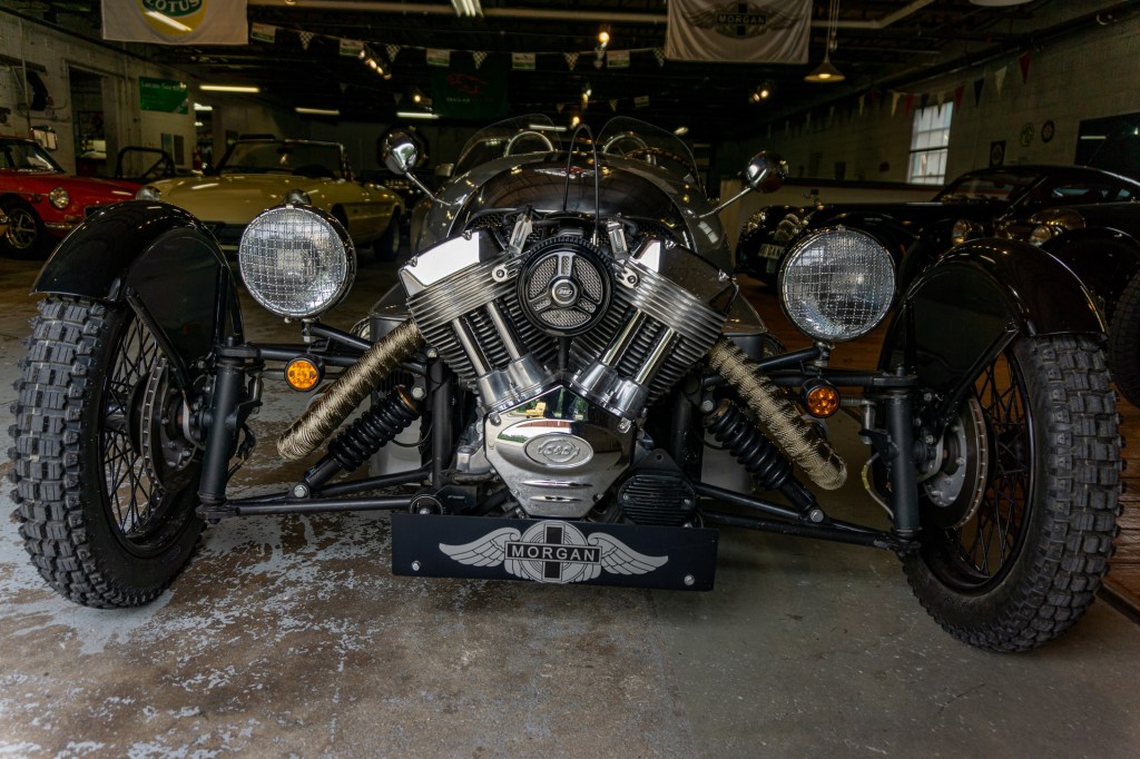 The front of a silver 2012 Morgan 3-Wheeler in a garage