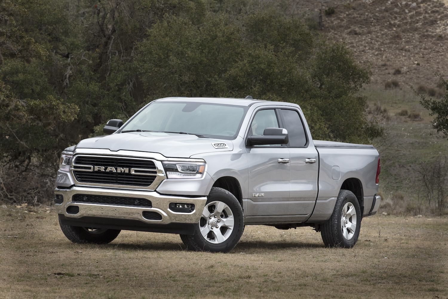 Silver 2019 Ram 1500 parked in a field. This fifth-generation pickup truck wears a Big Horn badge.