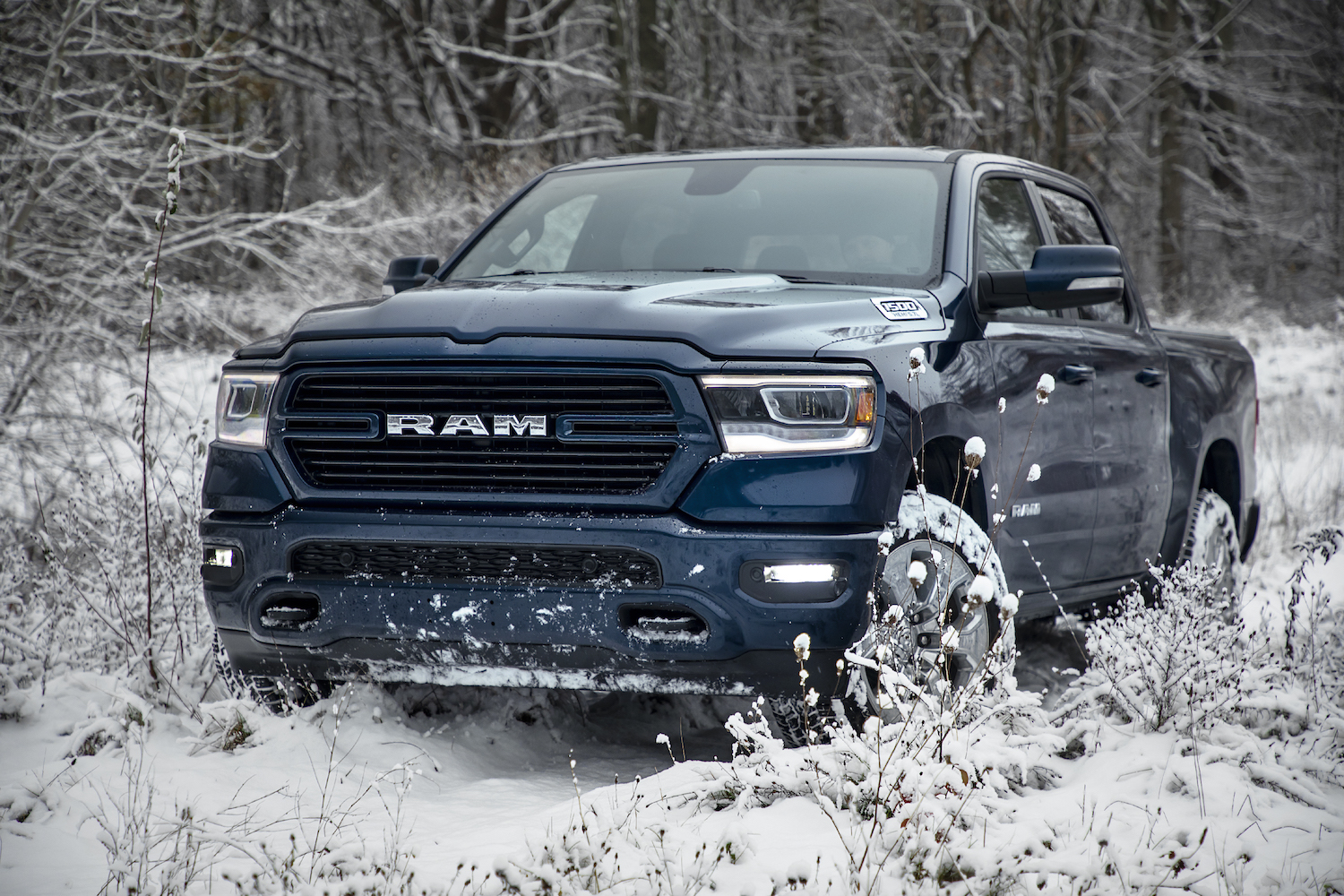 Blue Ram 1500 truck parked in the middle of snowy woods.