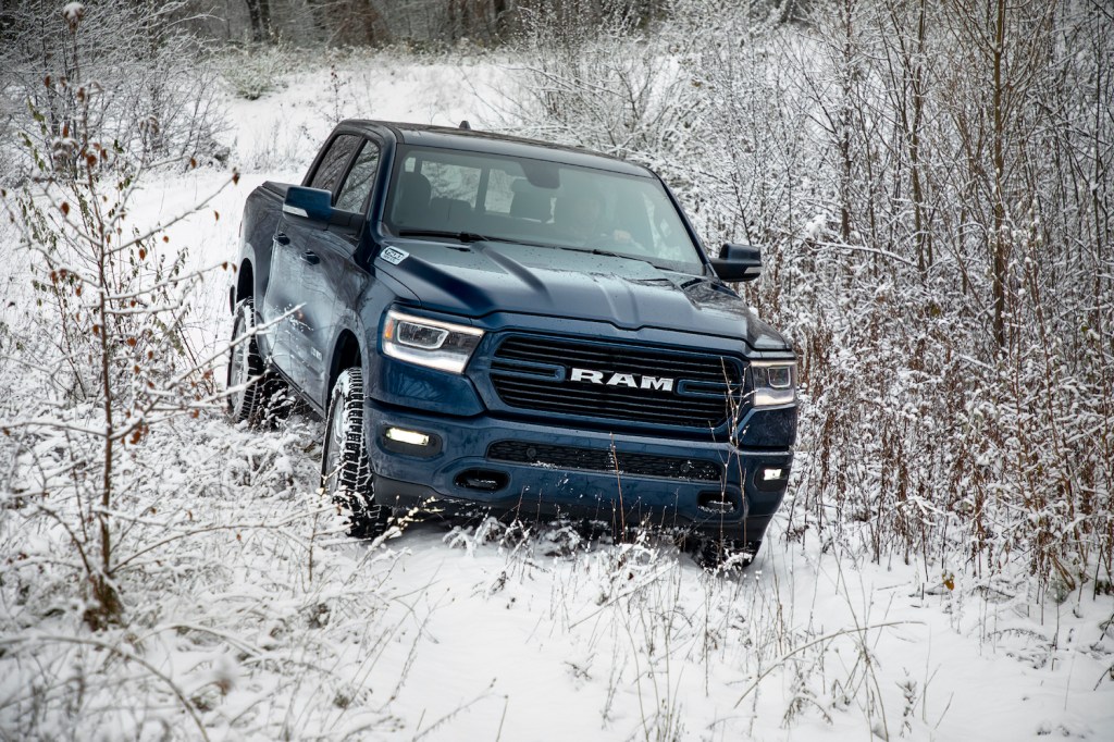Dark blue Ram pickup truck navigating a snow-covered trail in the woods.