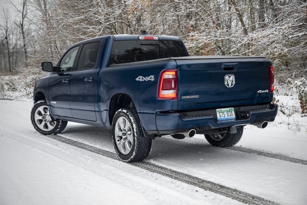 Dark blue Ram pickup truck parked on a snowy road in front of a forest.