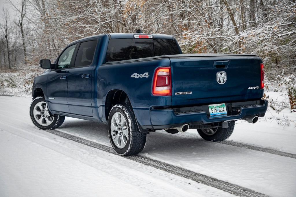 Dark blue Ram pickup truck parked on a snowy road in front of a forest.
