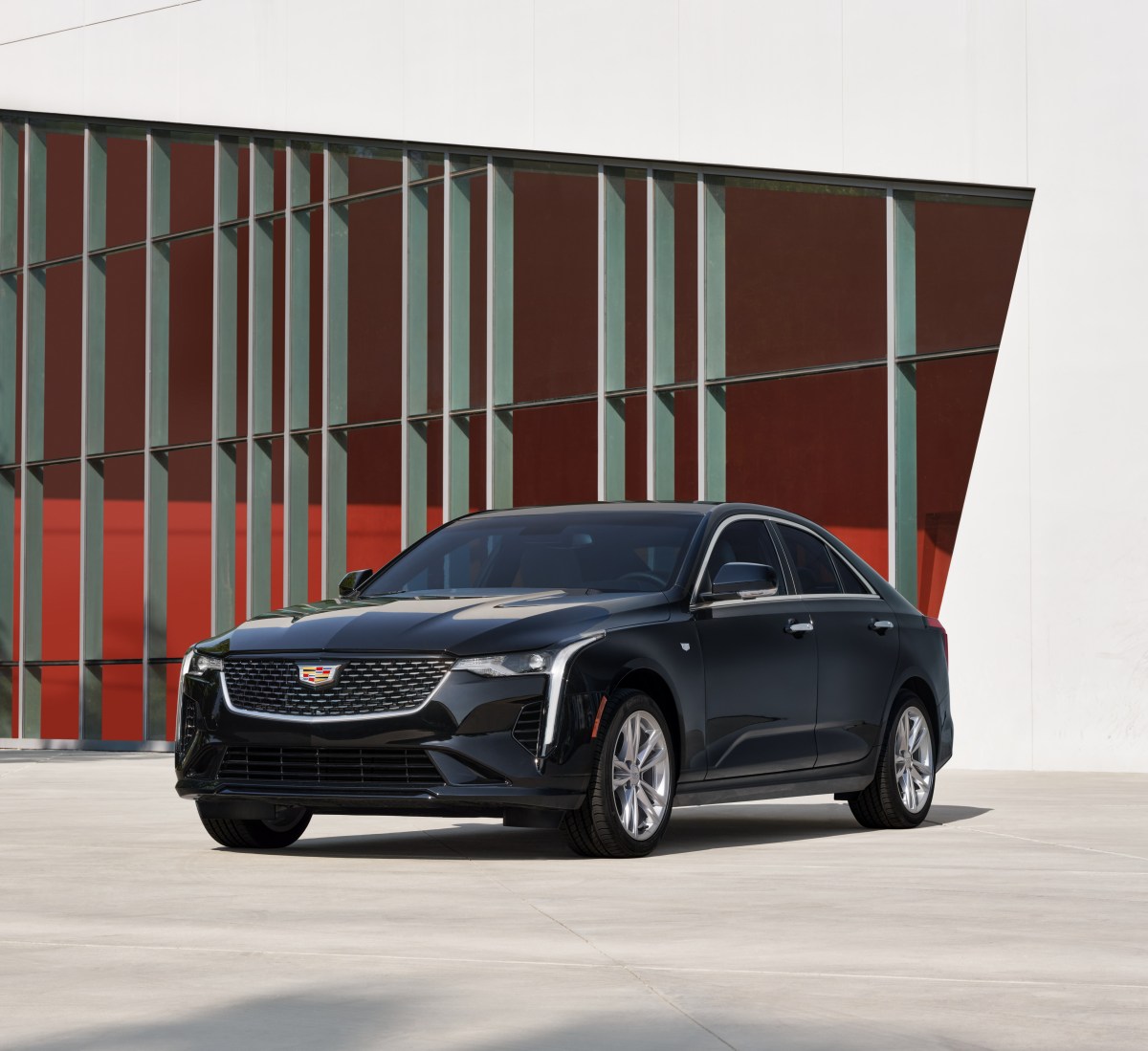A 3/4 front view of a black 2021 Cadillac CT4 sedan parked in front of a red and white building.
