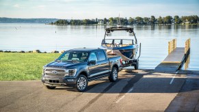 2021 Ford F-150 pickup truck backing a boat down a boat ramp next to a dock.