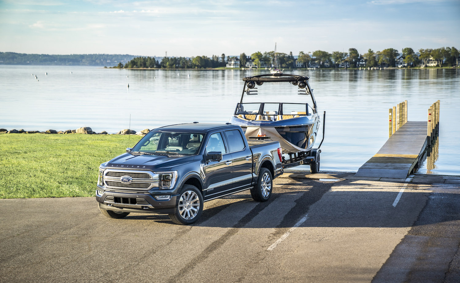 2021 Ford F-150 pickup truck backing a boat down a boat ramp next to a dock.