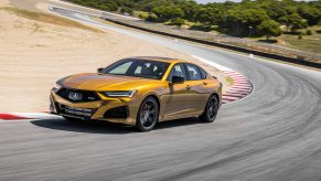 A 3/4 front view of a gold 2021 Acura TLX Type-S cornering on a race track