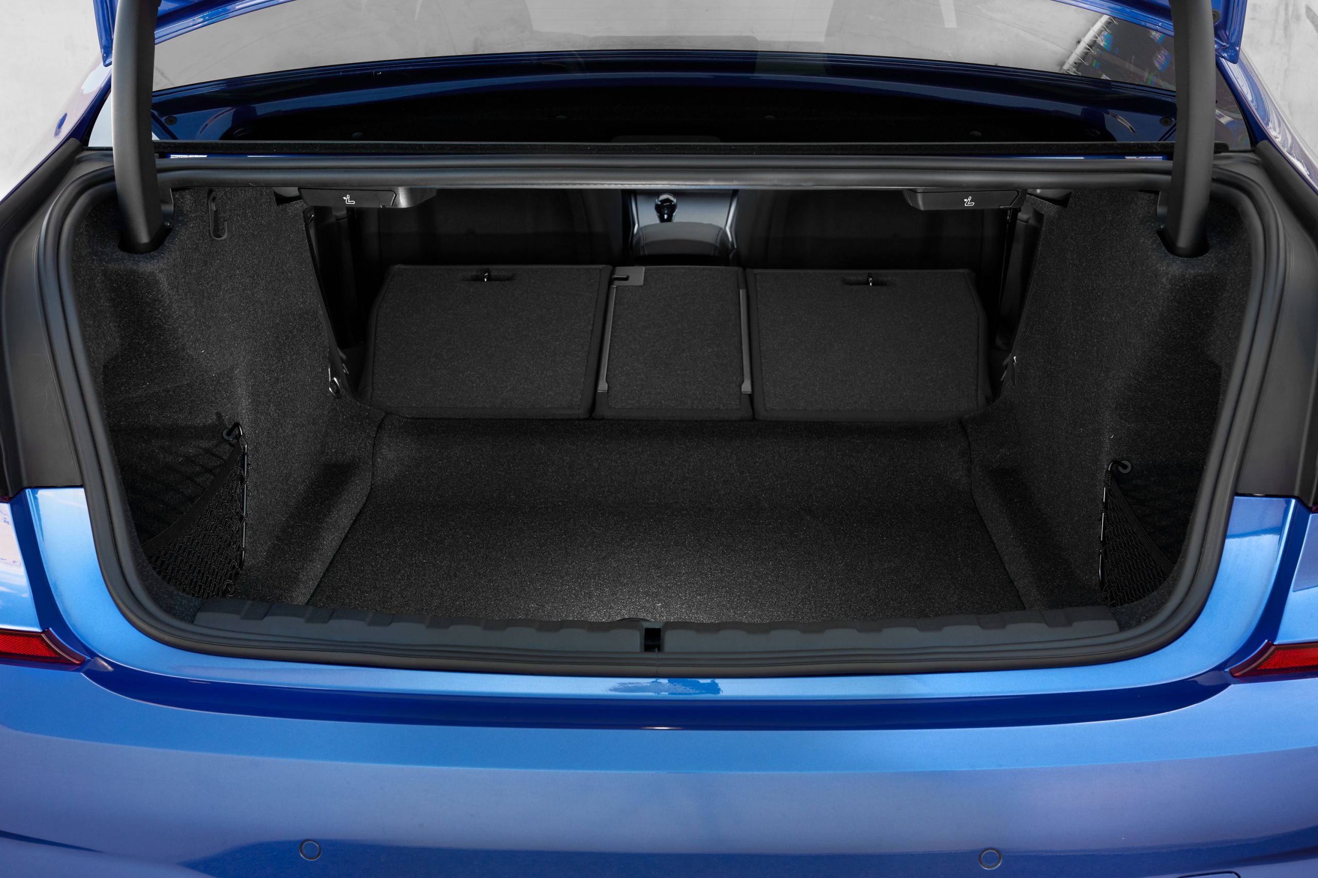 The trunk of a blue BMW 3 Series with the seats down