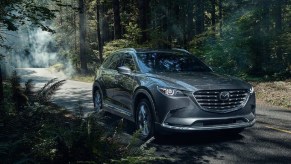 A dark blue 2022 Mazda CX-9 splashing through a puddle.