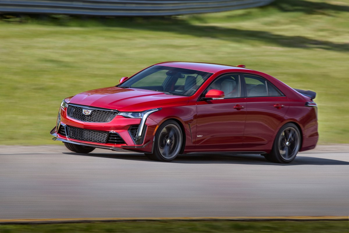 A 3/4 front and profile view of a red 2022 Cadillac CT4-V Blackwing cornering hard on a race track.
