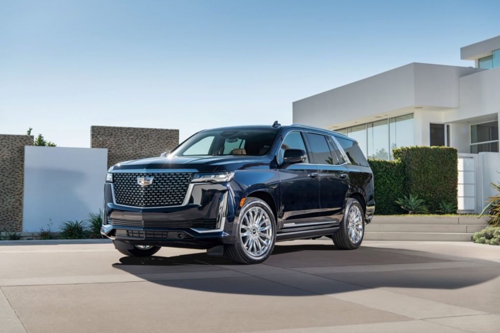 A black 2022 Cadillac Escalade parked in front of a square shaped building outdoors.