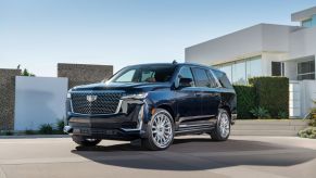 A black 2022 Cadillac Escalade parked in front of a square shaped building outdoors.