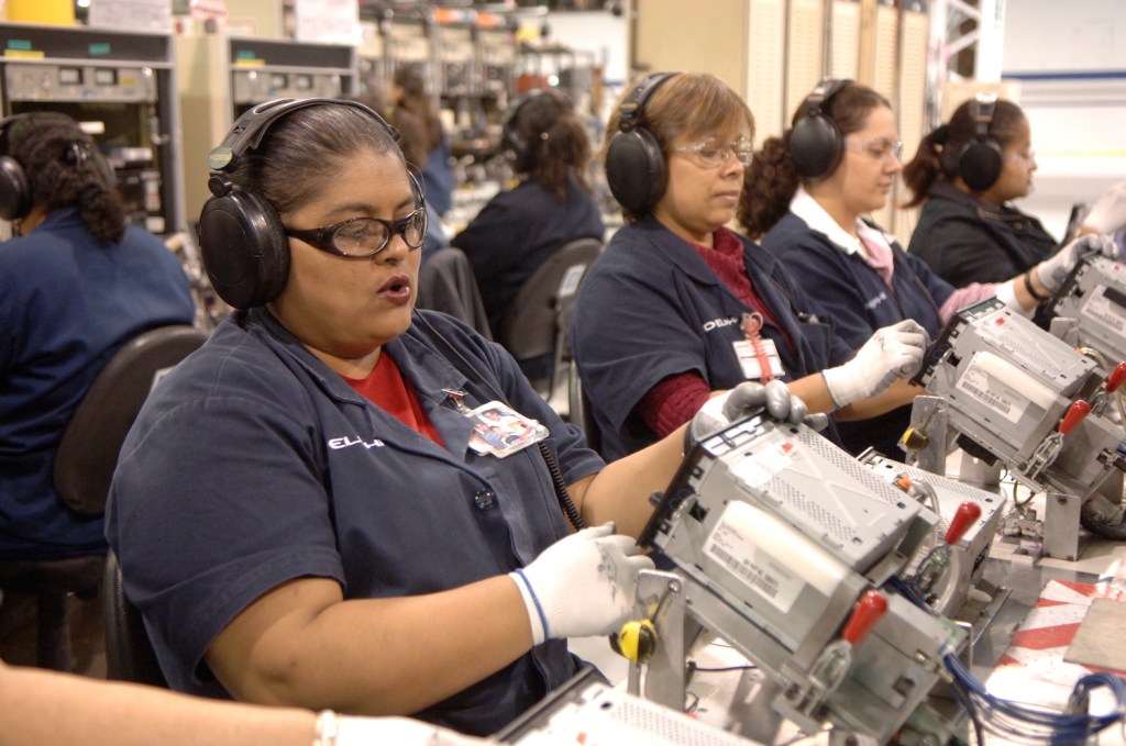 A row of Mexican women assembling car stereos for the GMC Sierra.