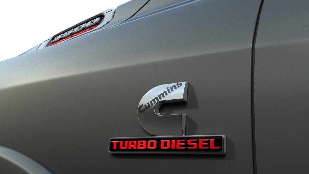 Detail shot of a Cummins Turbo Diesel badge on the side of a gray Dodge Ram pickup truck.