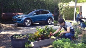 A blue 2022 Ford Escape with a man gardening next to it.