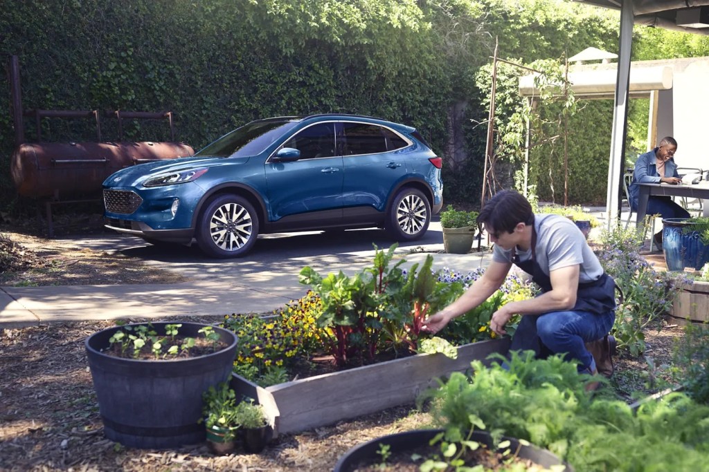 A blue 2022 Ford Escape with a man gardening next to it.