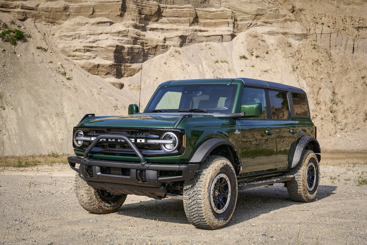 A 2022 Ford Bronco in Eruption Green parked in front of a dusty cliff