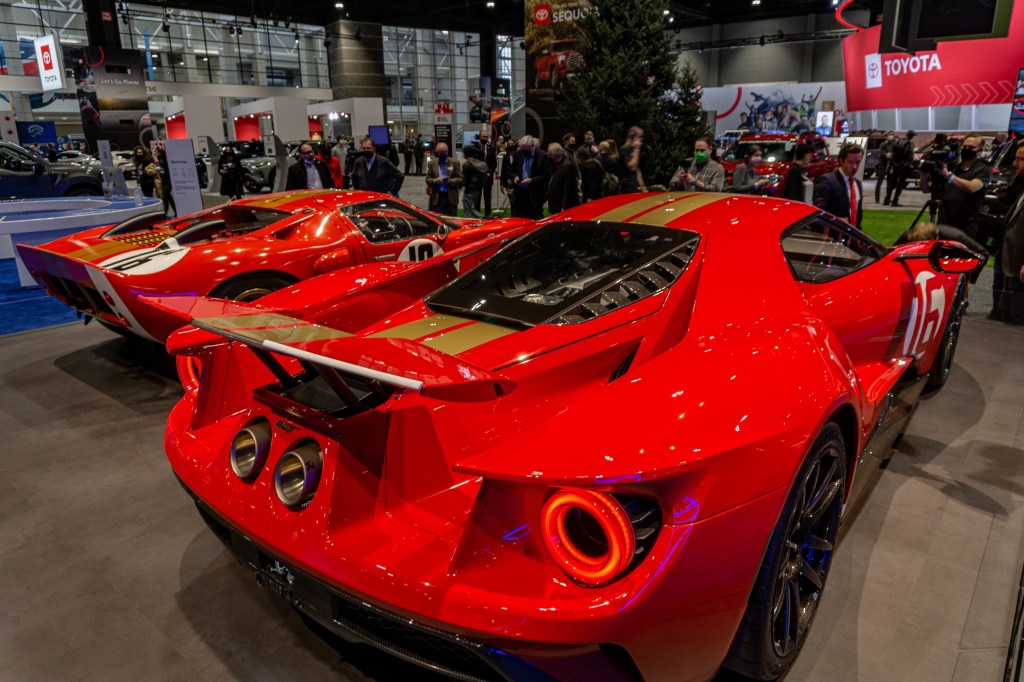The rear 3/4 view of the red-and-gold 2022 Ford GT Alan Mann Heritage Edition next to the red-and-gold 1966 Ford GT40 Mk I Lightweight 'AM GT-1'