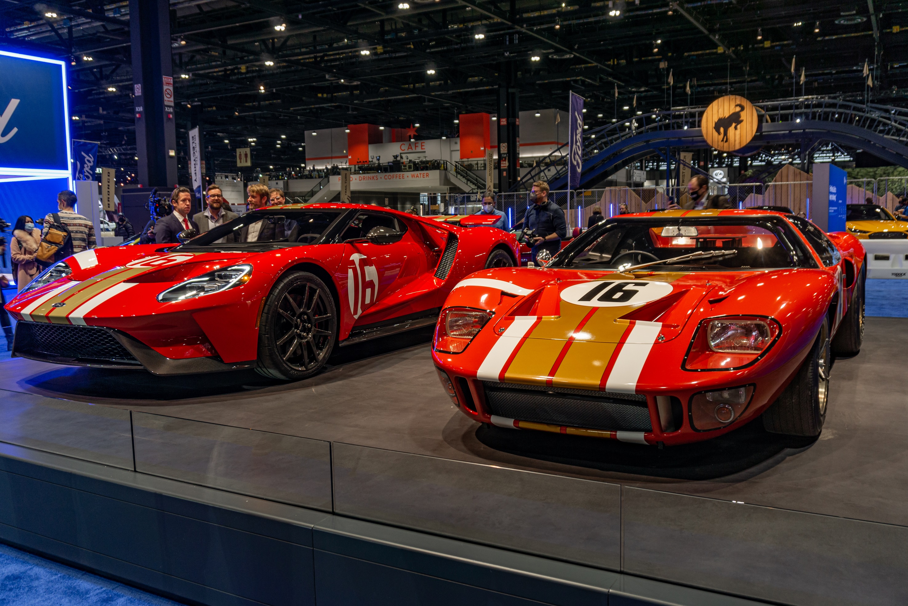 A red-and-gold 2022 Ford GT Alan Mann Heritage Edition next to the red-and-gold 1966 Ford GT40 Mk I Lightweight 'AM GT-1' on a stand