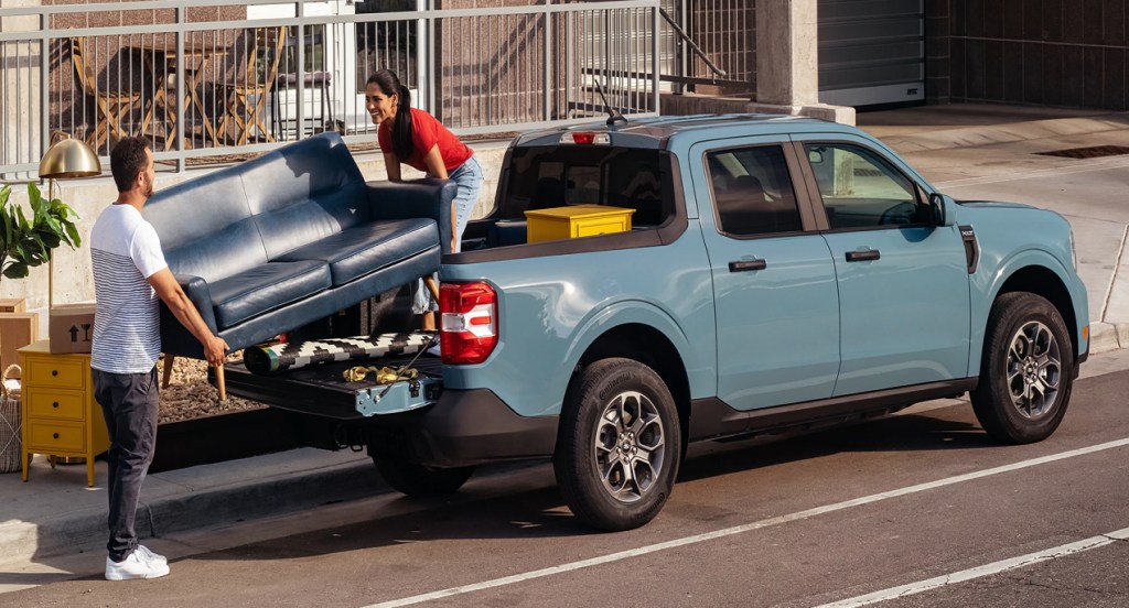 Couple loading a blue Ford Maverick with furniture