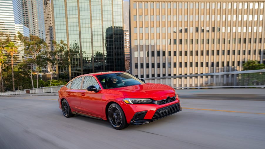 A red 2022 Honda Civic Sedan Sport with HPD Package drives through a city