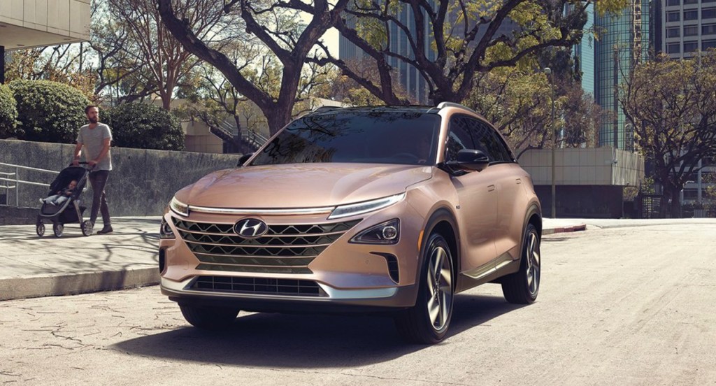A copper metallic 2022 Hyundai Nexo compact SUV is driving on the road.