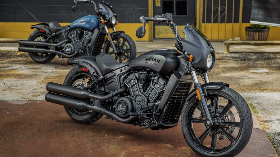 A matte-black 2022 Indian Scout Rogue in front of a blue one in a parking lot