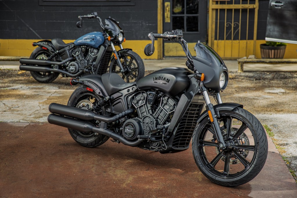 A matte-black 2022 Indian Scout Rogue in front of a blue one in a parking lot