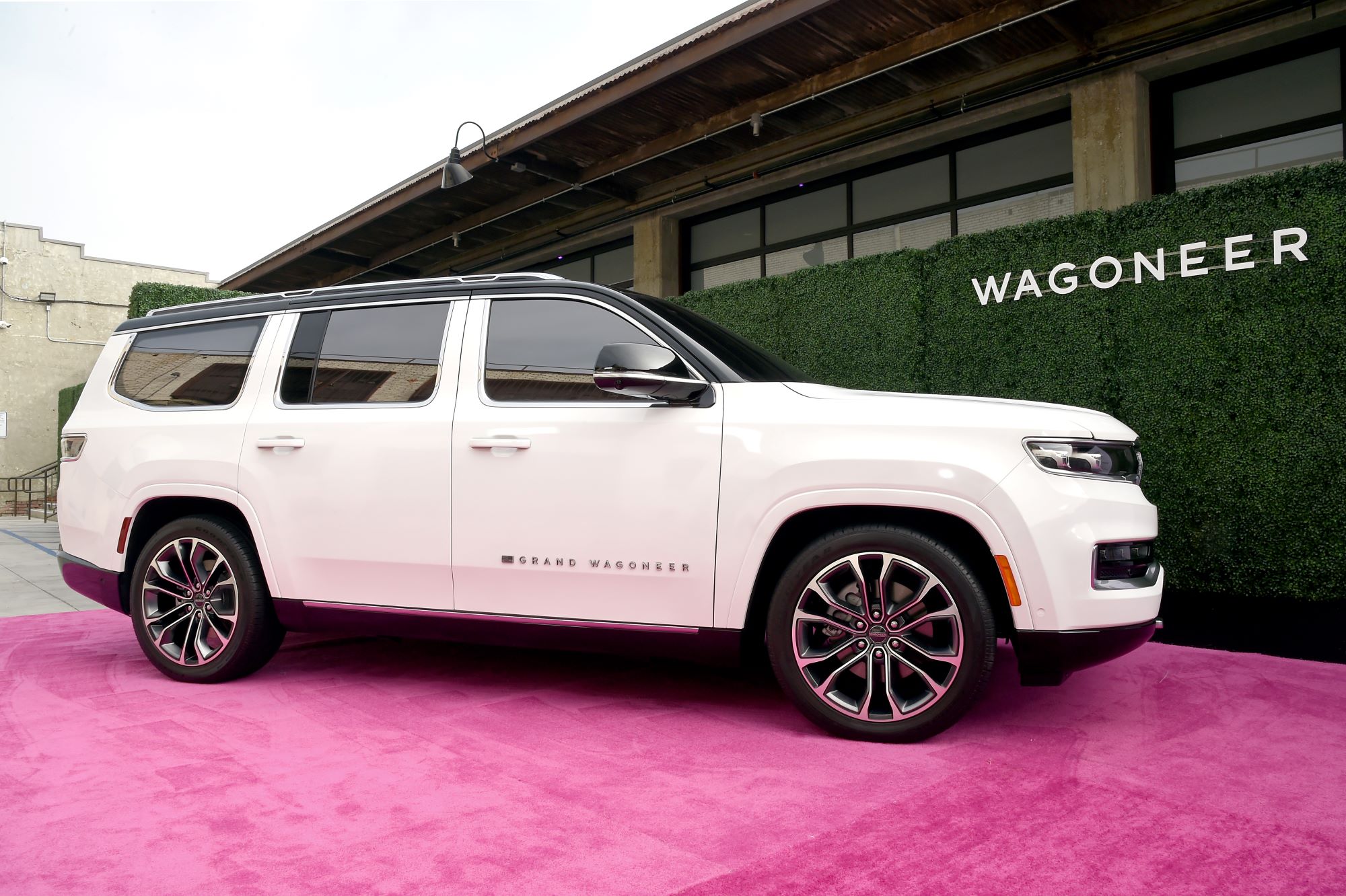 A white 2022 Jeep Grand Wagoneer in front of a building on a red carpet.