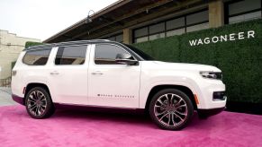 A white 2022 Jeep Grand Wagoneer in front of a building on a red carpet.