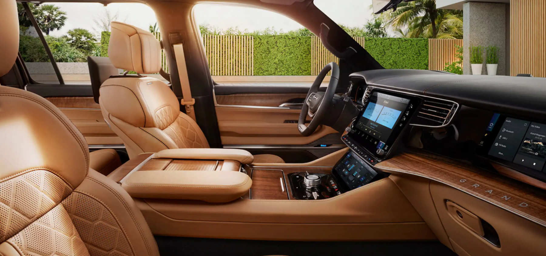 The interior front seat upholstery and dashboard technology layout of the 2022 Jeep Grand Wagoneer full-size luxury SUV