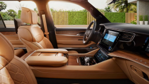 The interior front seat upholstery and dashboard technology layout of the 2022 Jeep Grand Wagoneer full-size luxury SUV