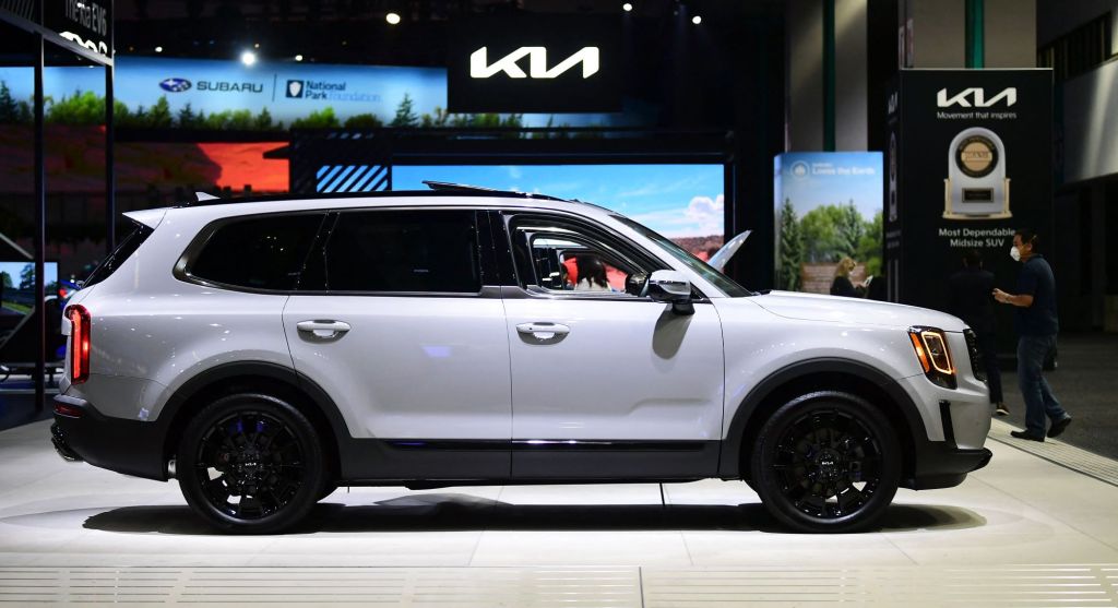A white 2022 Kia Telluride in an indoor environment with outdoor displays and a white Kia logo. 