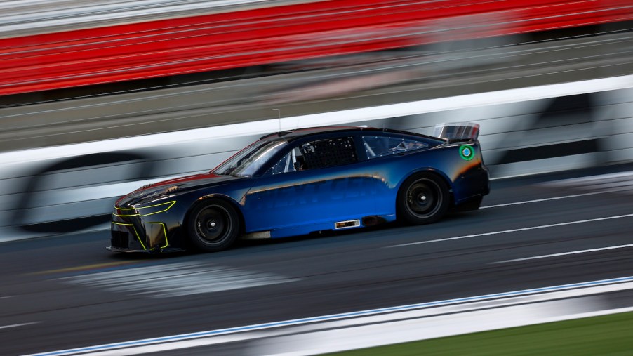 A blue NASCAR race car speeding down a racetrack, the background a blur.
