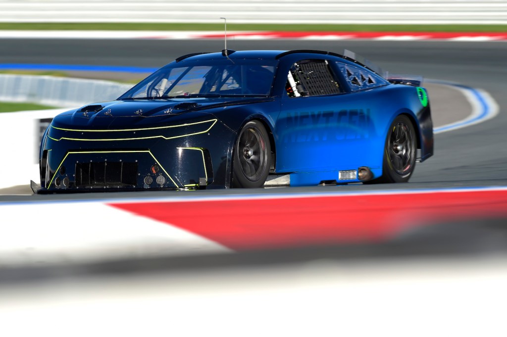 Blue prototype of NASCAR's Next Gen car testing at high speed on racetrack.