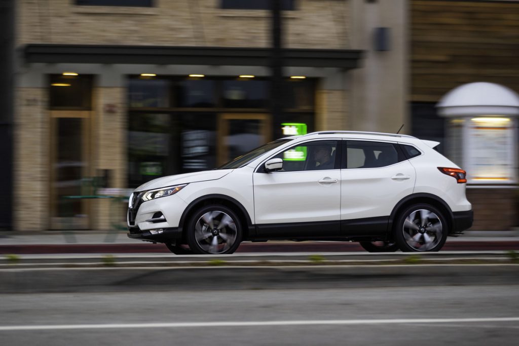 2022 Nissan Rogue Sport travels on a city street past storefronts