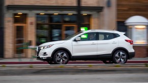 2022 Nissan Rogue Sport travels on a city street past storefronts